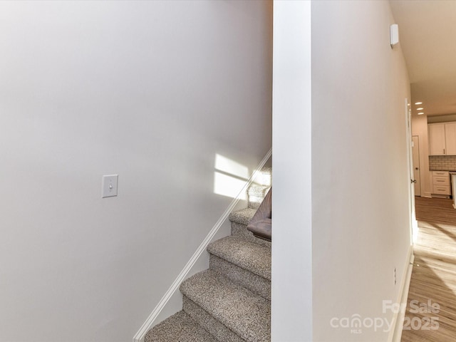 staircase featuring baseboards and wood finished floors