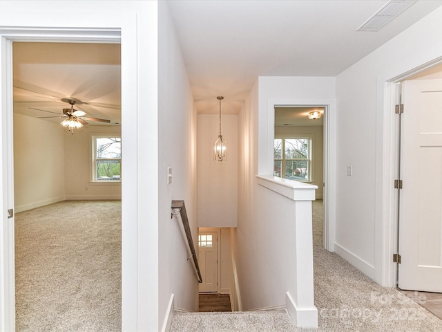 hall with visible vents, an upstairs landing, carpet, and an inviting chandelier