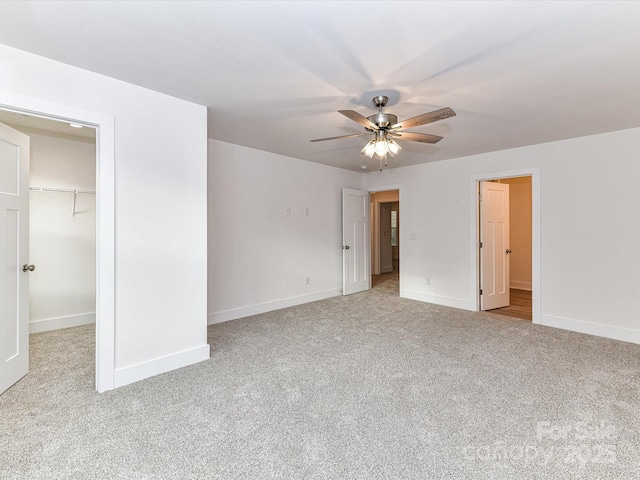 unfurnished bedroom with a spacious closet, ceiling fan, baseboards, carpet flooring, and a closet