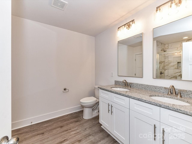 full bath with a stall shower, wood finished floors, visible vents, and a sink