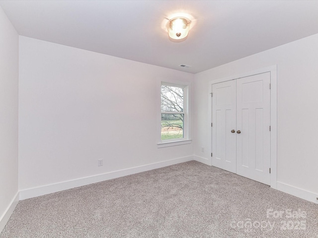 unfurnished bedroom with visible vents, baseboards, a closet, and carpet flooring