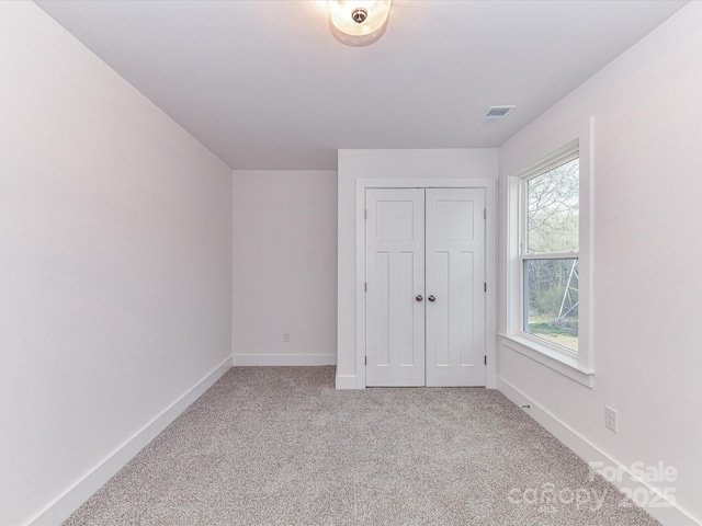 unfurnished bedroom featuring visible vents, baseboards, carpet, and a closet