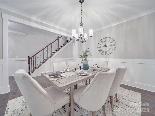 dining room with ornamental molding, an inviting chandelier, and dark wood-type flooring