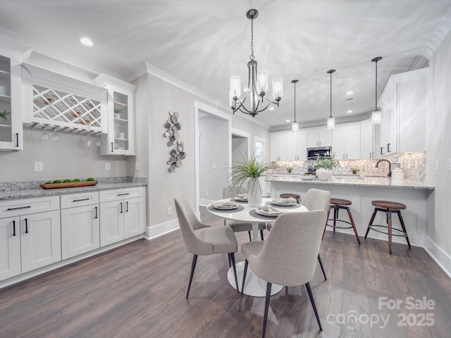 dining space with a chandelier, dark hardwood / wood-style floors, crown molding, and sink