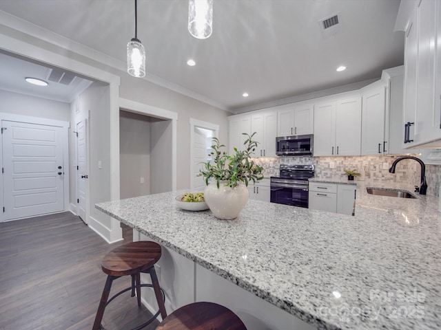 kitchen with light stone countertops, stainless steel appliances, sink, white cabinets, and hanging light fixtures