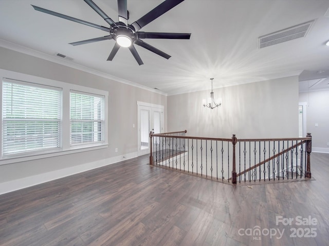 empty room featuring dark hardwood / wood-style flooring, ceiling fan with notable chandelier, and crown molding