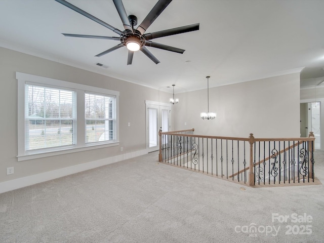 carpeted spare room featuring ceiling fan with notable chandelier and ornamental molding