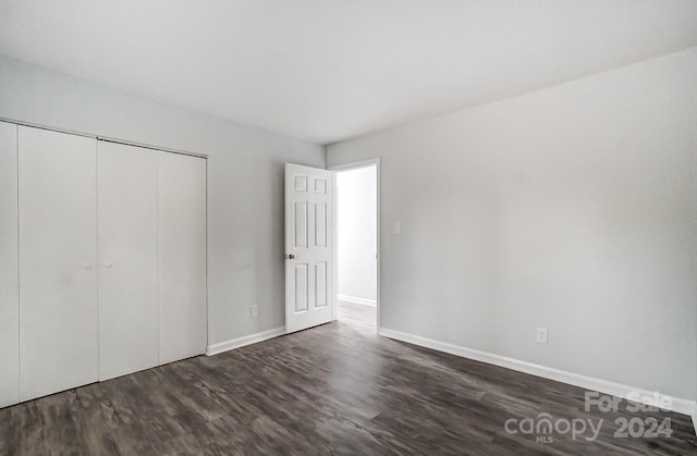 unfurnished bedroom with dark hardwood / wood-style flooring and a closet