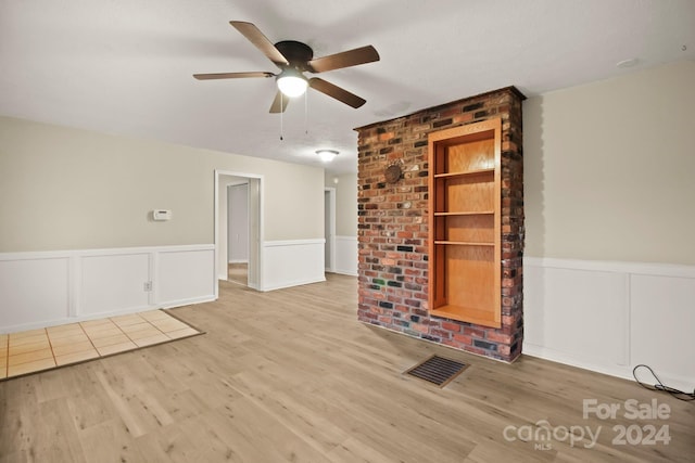 unfurnished room featuring a textured ceiling, light wood-type flooring, built in features, and ceiling fan