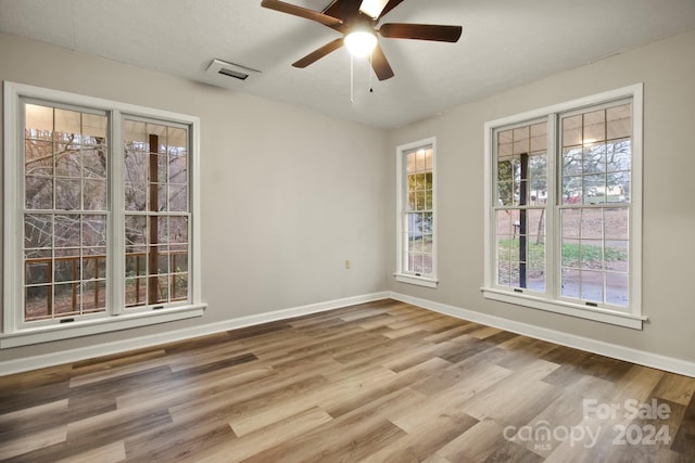 empty room with ceiling fan, light hardwood / wood-style floors, and a textured ceiling