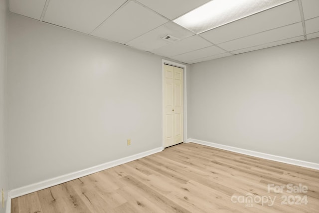 empty room featuring a paneled ceiling and light hardwood / wood-style floors