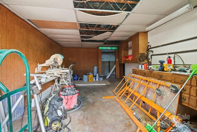 miscellaneous room featuring a workshop area, wooden walls, and concrete floors