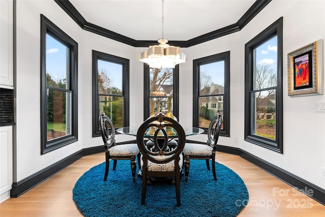 dining space with a notable chandelier, crown molding, light hardwood / wood-style flooring, and plenty of natural light