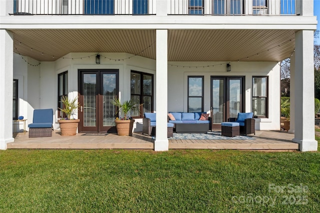 rear view of property with a balcony, outdoor lounge area, a yard, and french doors