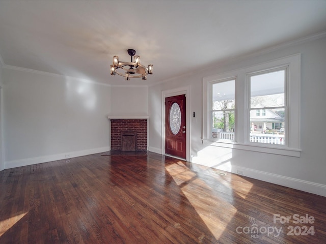 foyer entrance featuring ornamental molding, dark wood-type flooring, a brick fireplace, and a notable chandelier