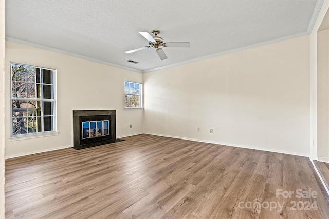 unfurnished living room with a textured ceiling, light hardwood / wood-style floors, ceiling fan, and crown molding