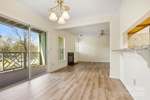 unfurnished dining area with ceiling fan with notable chandelier, light wood-type flooring, and ornamental molding