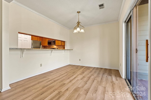 unfurnished living room with crown molding, light hardwood / wood-style flooring, a textured ceiling, and an inviting chandelier