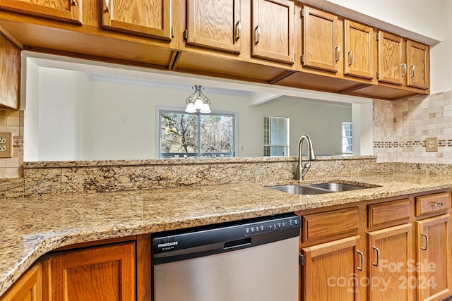 kitchen with decorative backsplash, dishwasher, light stone counters, and sink