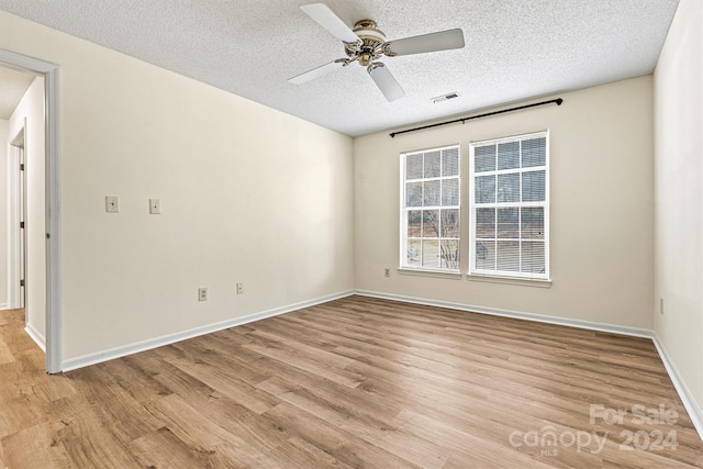 unfurnished room featuring a textured ceiling, light hardwood / wood-style flooring, and ceiling fan