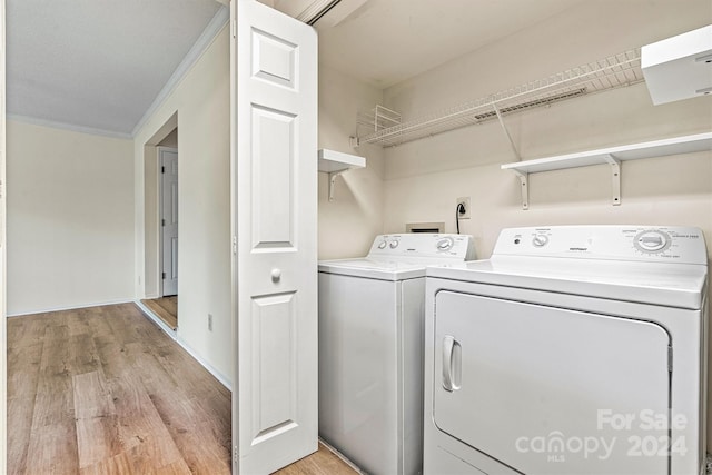 washroom featuring ornamental molding, washer and dryer, and light wood-type flooring