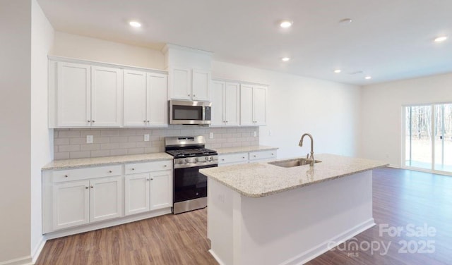 kitchen featuring sink, a kitchen island with sink, white cabinets, and appliances with stainless steel finishes