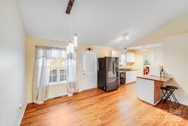 kitchen with black dishwasher, freestanding refrigerator, white cabinetry, a sink, and a peninsula