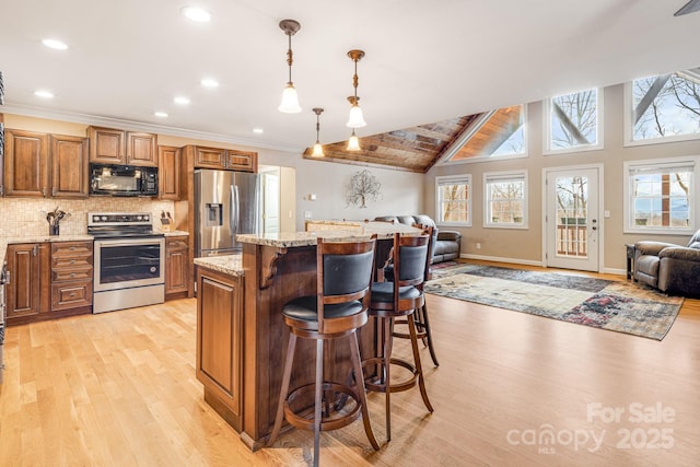 kitchen featuring pendant lighting, a breakfast bar, a center island, light stone countertops, and appliances with stainless steel finishes