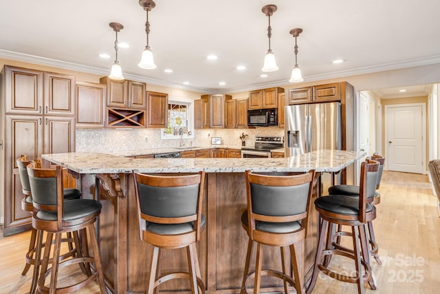 kitchen with light stone counters, stainless steel appliances, a breakfast bar area, hanging light fixtures, and a large island