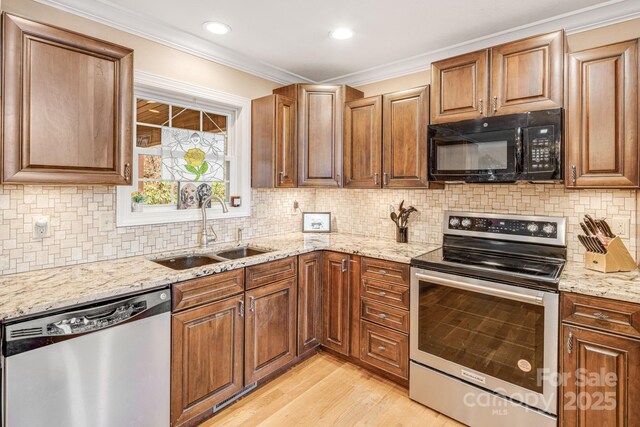 kitchen with backsplash, light stone countertops, sink, and appliances with stainless steel finishes