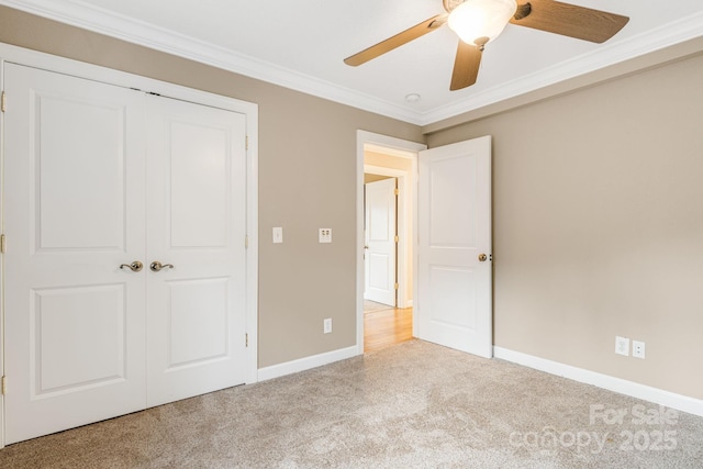 unfurnished bedroom featuring carpet, a closet, ornamental molding, and ceiling fan