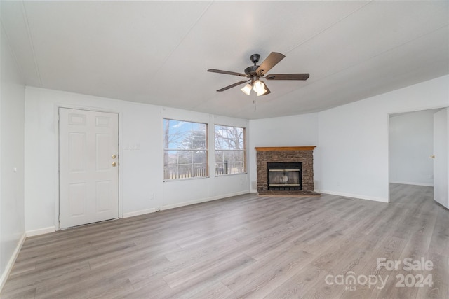 unfurnished living room featuring ceiling fan, lofted ceiling, a fireplace, and light hardwood / wood-style flooring