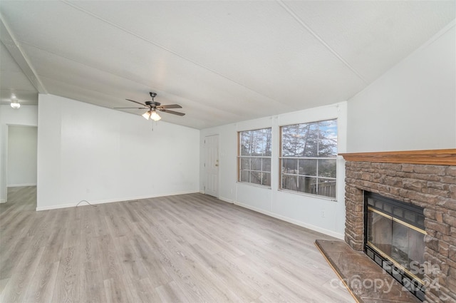 unfurnished living room with ceiling fan, a stone fireplace, light wood-type flooring, and lofted ceiling