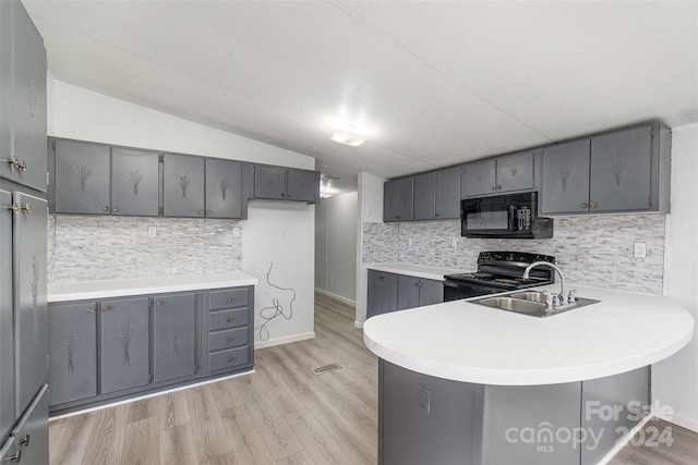 kitchen featuring black appliances, lofted ceiling, gray cabinetry, and kitchen peninsula