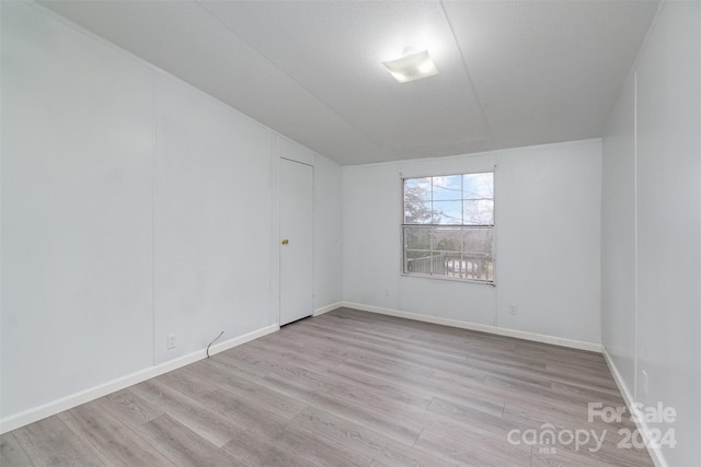 empty room featuring a textured ceiling and light hardwood / wood-style floors