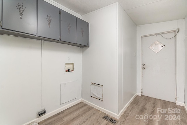 clothes washing area featuring washer hookup, cabinets, and light wood-type flooring