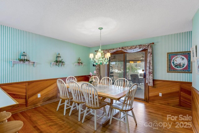 dining room featuring wood-type flooring, a chandelier, and a textured ceiling