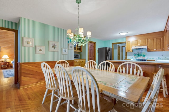 dining space with a textured ceiling, a notable chandelier, and light hardwood / wood-style floors