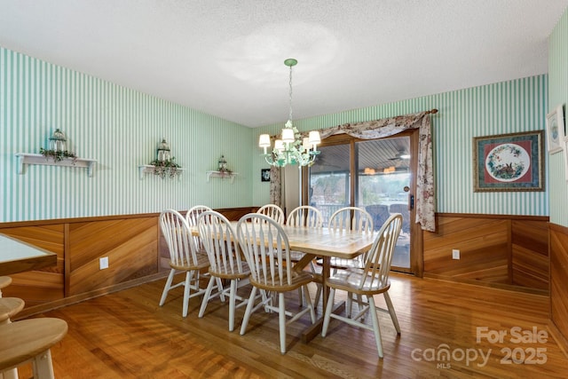 dining space featuring wood-type flooring, a textured ceiling, and an inviting chandelier