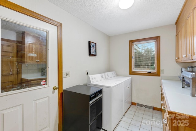 clothes washing area with cabinets, separate washer and dryer, a textured ceiling, and light tile patterned floors