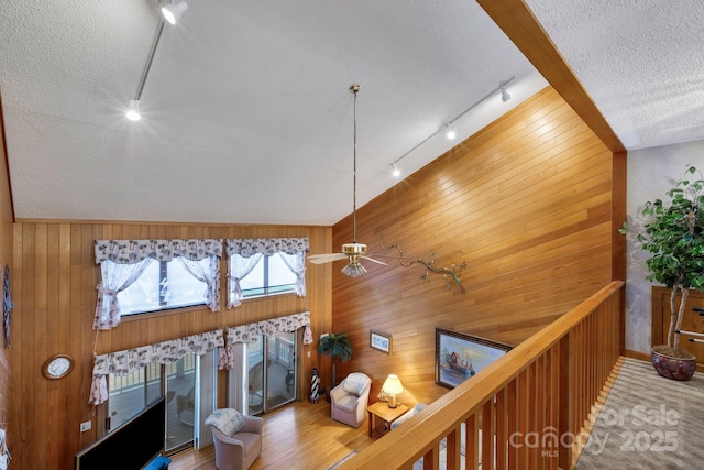 living room with track lighting, a textured ceiling, and wood walls