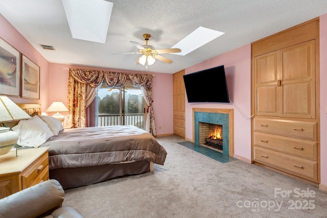 bedroom with a skylight, access to outside, light colored carpet, and ceiling fan