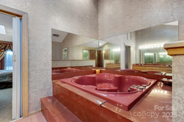 bathroom with tile patterned flooring and tiled tub