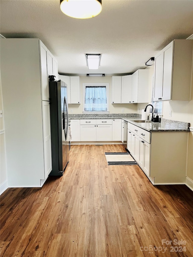 kitchen featuring stainless steel appliances, white cabinetry, light hardwood / wood-style floors, and sink