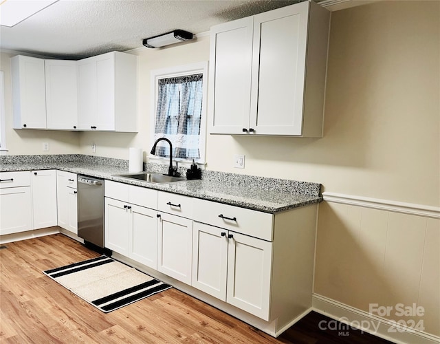 kitchen featuring white cabinetry, sink, stainless steel dishwasher, and light hardwood / wood-style floors