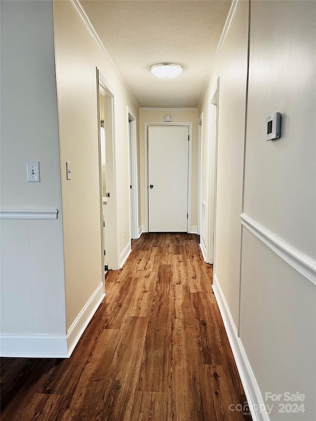 hallway featuring crown molding, hardwood / wood-style floors, and a textured ceiling