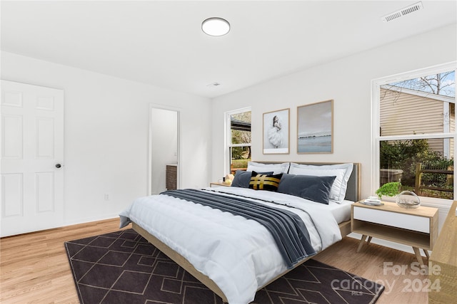 bedroom with multiple windows and hardwood / wood-style flooring