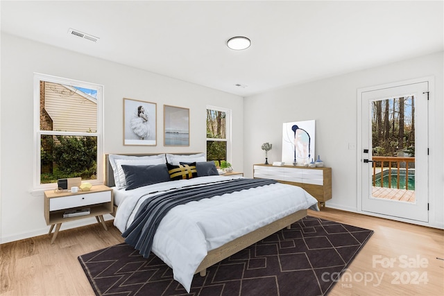 bedroom with hardwood / wood-style floors, access to outside, and multiple windows