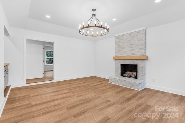 unfurnished living room featuring a fireplace, a chandelier, and light hardwood / wood-style flooring