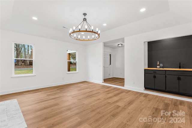 unfurnished living room with sink, a chandelier, and hardwood / wood-style flooring